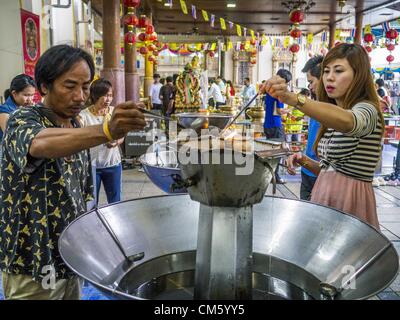 12 octobre 2012 - Rai Khring, Nakhon Pathom, Thaïlande - Thai bouddhistes verser de l'huile dans une lampe pour rendre au Wat Rai Khring mérite dans la province de Nakhon Pathom. Wat Rai Khring a été construit en 1791, l'Abbé de l'époque, Somdej Phra Phuttha Chan (Pook), du nom de ce temple après le district. Lorsque la construction a été terminée, l'image du Bouddha a été portée à partir d'un autre temple et énoncés ici. Plus tard, les sections locales du nom de l'image « oeLuang Khingâ Pho Wat Rai€. L'image du Bouddha est de style Chiang Saen et est supposé avoir été construit par Lanna Thai et Lan Chang artisans. (Crédit Image : © Jack Kurtz/ZUMAPRESS.com) Banque D'Images