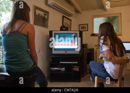 Deux jeunes femmes regardent la télévision comme un commandement du front de rupture Accueil alarmes alerte programmes réguliers d'information des téléspectateurs d'un tremblement de percer et de fournir des instructions d'urgence. Jérusalem, Israël. 21-Octobre-2012. Une semaine d'exercice séisme, le plus important jamais dans l'histoire du pays, commence et se diversifie : scénarios d'urgence y compris la destruction, raz de marée en Méditerranée, 7 000 morts et plus de 170,00 personnes déplacées. Banque D'Images