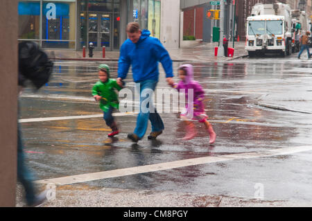 New York, NY - 29 Oct 2012 d'un père avec deux petits enfants en toute hâte la 8e Rue, dans l'East Village, pendant l'Ouragan Sandy Banque D'Images