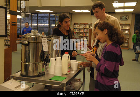 1 novembre 2012 l'Ouragan Sandy Jour 4 : Avec une grande partie de la côte Est des Etats-Unis (y compris la banlieue de New York toujours privés d'électricité, deux jeunes résidents de Pleasantville, NY, Anisha Chandy et son meilleur ami Iman Behbehani, les deux 11, prendre le thé de turco-vénitienne gratuit fourni par le Mt. Bibliothèque agréable pendant que leurs mères optimiser leurs téléphones portables et autres appareils. Les deux familles sont toujours sans électricité. Bibliothécaire de référence Alexa Brandenberg, de Tarrytown, NY et commis de bibliothèque Michael Walsh de Chappaqua, NY chat avec les filles. La bibliothèque a prolongé leurs heures et fourni les boissons gratuit pour aider les personnes Banque D'Images