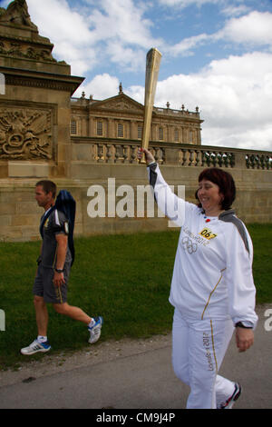 Le Derbyshire, Royaume-Uni. Le vendredi 29 juin 2012. Porteur de Flambeau olympique, Helen Hopkinson en passant par le Bastion mur de la demeure seigneuriale, Chatsworth House, siège du duc de Devonshire Banque D'Images