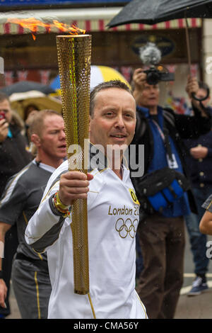 Northampton UK. 2 juillet 2012. Andy Wightman porte le flambeau olympique à St Giles Street en face de la ville de Northampton Guildhall Centre, comme la pluie commence. Banque D'Images