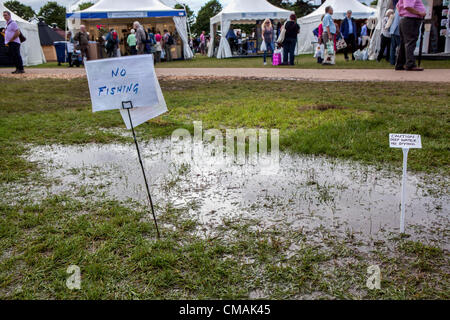 Hampton Court, Royaume-Uni. Mercredi 4 juillet 2012. La pluie continue de tomber dans le Royaume-Uni, mais les exposants n'ont pas perdu leur sens de l'humour comme des signes dans des flaques boueuses démontré. Le Hampton Court Flower Show est le plus grand spectacle de fleurs dans le monde et a lieu chaque année en juillet. Il est géré par la Royal Horticultural Society et est érigée sur les côtés nord et sud de l'eau à Hampton Court Palace. Le premier spectacle a été en 1990. Banque D'Images