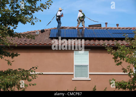 19 juillet 2012 - Aliso Viejo, Californie, États-Unis - les travailleurs de la construction d'installer des panneaux solaires sur une maison résidentielle toiture en Aliso Viejo, Californie. Location solaire pourrait être la section la plus forte croissance de l'énergie renouvelable le commerce comme 73  % des Californiens qui repose sur leur propriété PV solaire utilisent maintenant les entreprises de location. Des entreprises comme SunRun, Ville solaire, Sungevity, et l'énergie solaire la location de Californie sont entrés sur le marché de façon agressive. L'hypothèse que l'électricité du réseau les prix continueront d'augmenter à 7  %, un chiffre souvent cité par les sociétés de leasing, pourrait ne pas tenir dans le moyen terme. D Banque D'Images