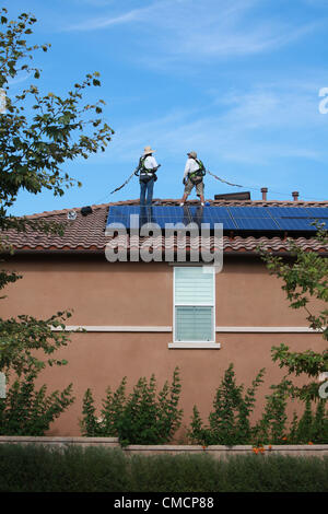 19 juillet 2012 - Aliso Viejo, Californie, États-Unis - les travailleurs de la construction d'installer des panneaux solaires sur une maison résidentielle toiture en Aliso Viejo, Californie. Location solaire pourrait être la section la plus forte croissance de l'énergie renouvelable le commerce comme 73  % des Californiens qui repose sur leur propriété PV solaire utilisent maintenant les entreprises de location. Des entreprises comme SunRun, Ville solaire, Sungevity, et l'énergie solaire la location de Californie sont entrés sur le marché de façon agressive. L'hypothèse que l'électricité du réseau les prix continueront d'augmenter à 7  %, un chiffre souvent cité par les sociétés de leasing, pourrait ne pas tenir dans le moyen terme. D Banque D'Images