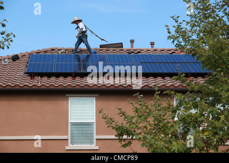 19 juillet 2012 - Aliso Viejo, Californie, États-Unis - les travailleurs de la construction d'installer des panneaux solaires sur une maison résidentielle toiture en Aliso Viejo, Californie. Location solaire pourrait être la section la plus forte croissance de l'énergie renouvelable le commerce comme 73  % des Californiens qui repose sur leur propriété PV solaire utilisent maintenant les entreprises de location. Des entreprises comme SunRun, Ville solaire, Sungevity, et l'énergie solaire la location de Californie sont entrés sur le marché de façon agressive. L'hypothèse que l'électricité du réseau les prix continueront d'augmenter à 7  %, un chiffre souvent cité par les sociétés de leasing, pourrait ne pas tenir dans le moyen terme. D Banque D'Images