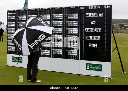 23 juillet 2012, Club de golf Kilmarnock (Barassie), Troon, Ayrshire. Tableau de bord du tournoi de qualification du Championnat d'Open Royal and anciens Senior, qui se tiendra à Turnberry. Le concurrent se protège sous un parapluie portant le logo Ping ed pendant qu'il vérifie les heures de départ sur le tableau de scores. Banque D'Images