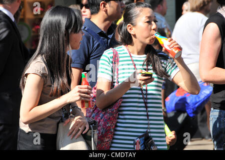 Oxford Street, Londres, Royaume-Uni. 26 juillet 2012. Les membres de la foule de boire des bouteilles de Coca Cola un sponsor des Jeux, comme le relais de la Flamme Olympique passe le long d'Oxford Street au centre de Londres et l'approche de la fin de son voyage de 8 000 km à travers la Grande-Bretagne. Banque D'Images