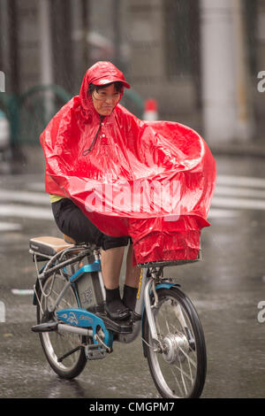 Un cycliste tente de faire des progrès au cours des vents en rafales comme Typhon Haikui a atteint les côtes de l'est de la Chine d'effectuer vie de 23 millions de personnes dans le centre des affaires de Shanghai le 8 août 2012 à Shanghai, Chine. Banque D'Images