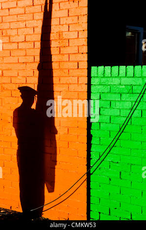 Une ombre tombe sur un mur peint en orange et vert d'une jeune fille habillé en uniformes paramilitaires, tenant un drapeau dans le cadre d'une partie couleur Crédit : Stephen Barnes/Alamy Live News Banque D'Images