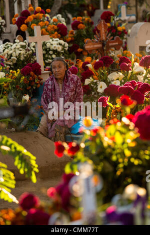 Une vieille femme mexicaine s'assied à la tombe d'un être cher à la riche décoration San Antonillo Castillo Velasco Cemetery pendant le jour de la Fête des Morts connus en espagnol comme d'un de muertos le 3 novembre 2013 à Ocotlan, Oaxaca, Mexique. Le cimetière a un concours du meilleur décorées tombe. Banque D'Images