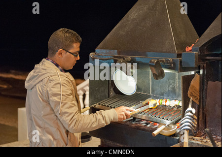 Chef de la cuisson des aliments sur le front de mer de Benalmadena à l'extérieur sur un barbecue au charbon de bois chaud Banque D'Images