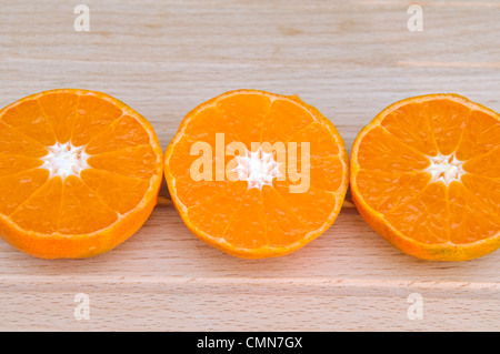 Portrait de trois moitiés d'orange Clémentine, qui sont une variété de mandarine, affiché sur une planche à découper Banque D'Images