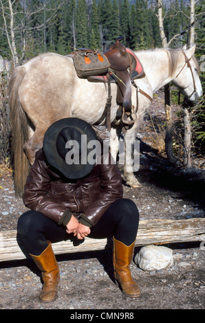 Un trail rider sur une aventure de vacances prend un pan de midi avec son cheval pendant une visite pack voyage dans le parc national de Banff en Alberta, Canada. Banque D'Images