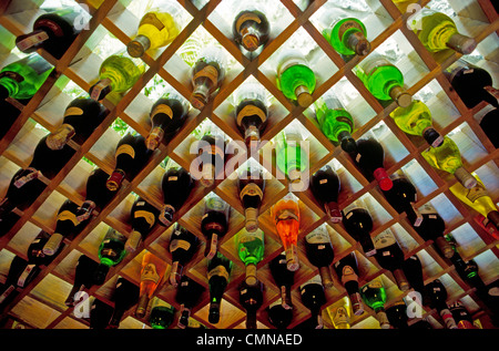 Des bouteilles de vin sont affichées dans un casier à vin en bois qui est contre un mur rétro-éclairé dans un restaurant en Suisse. Banque D'Images