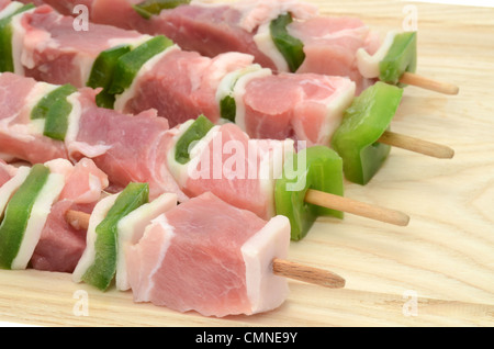 Brochettes de porc frais de pose sur un kebab planche à découper en bois Banque D'Images