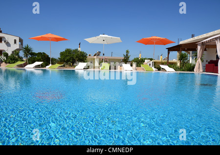 Piscine extérieure avec chaises longues et parasols sous un ciel bleu Banque D'Images