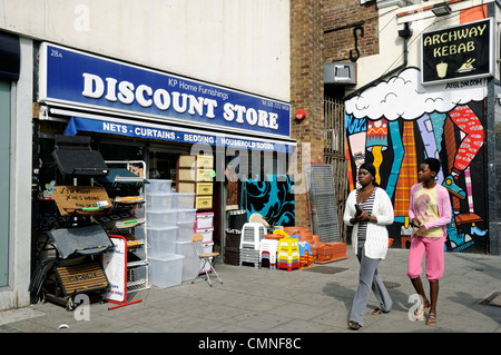 Deux dames passant devant un magasin à prix réduits avec exposition à l'extérieur sur Junction Road Archway London Borough of Islington England UK Banque D'Images