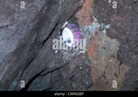 Géocache exposée cachée dans une cavité de paroi rocheuse à l'intérieur d'une grotte volcanique, montrant conteneur et journal de bord. Banque D'Images