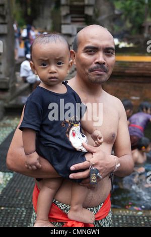 Père et fils fidèles priant et baignade à Tirtal Empul Temple, Bali, Indonésie Banque D'Images