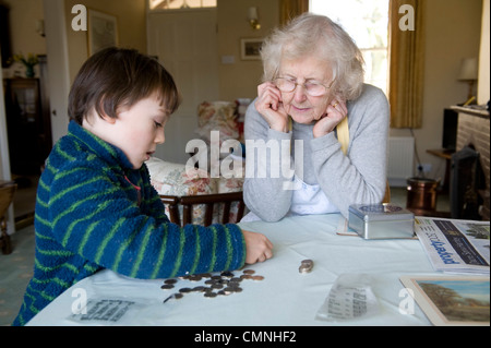 Grand-mère et son petit-fils à compter des pièces à table à manger Banque D'Images