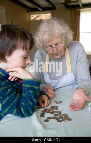 Grand-mère et son petit-fils à compter des pièces à table à manger Banque D'Images