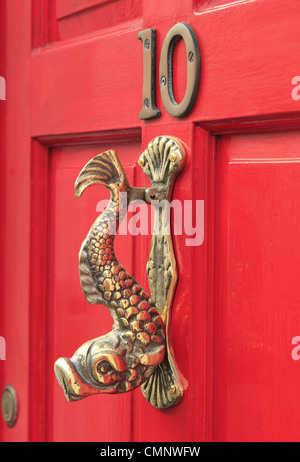 Un heurtoir en laiton en forme de poisson sur une porte rouge numéro 10 10 dans la ville de Lewes, East Sussex, Angleterre Banque D'Images