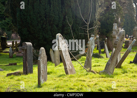 Les pierres tombales se penchant à différents angles, causant l'affaissement des tombes à tomber. Banque D'Images