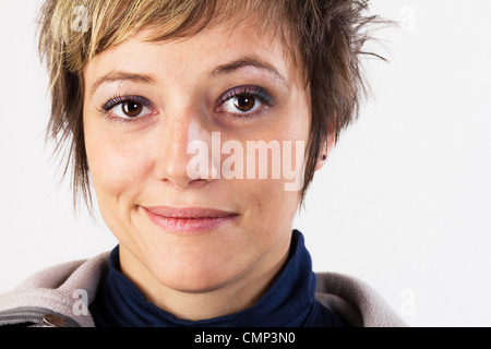 Belle jeune femme fait un drôle de visage, l'expression féminine avec un léger sourire. Studio shot sur un fond blanc. Banque D'Images