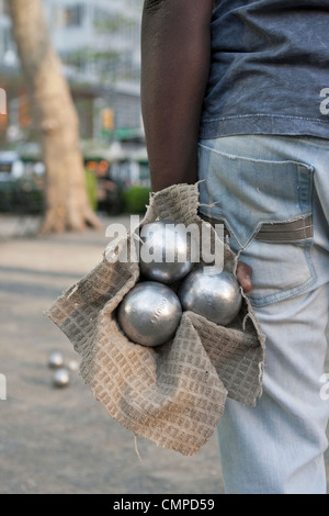 Un homme détient 3 boules en attendant son tour dans un jeu de pétanque à Bryant Park à New York. Banque D'Images