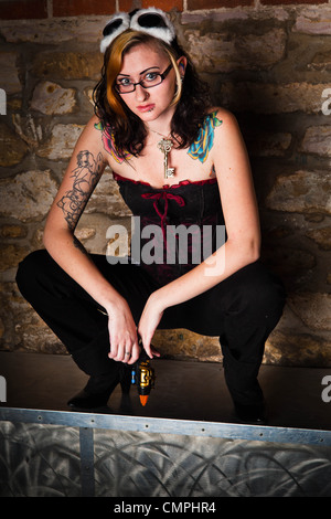 Une femme brune vêtue de vêtements steampunk themed pose avec des lunettes sur la tête. Banque D'Images