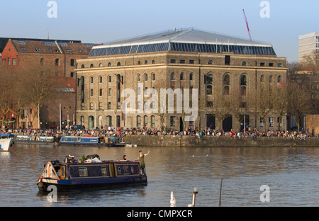 Les gens profiter du soleil sur l'harbourside en dehors de la galerie Arnolfini à Bristol. Le centre est un hotspot culturelle pour la ville. Banque D'Images