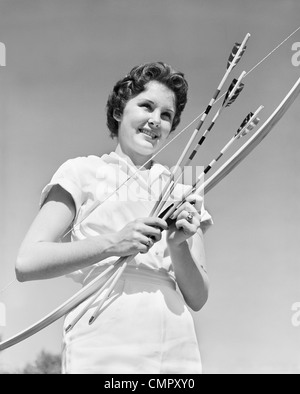 1950 SMILING YOUNG WOMAN HOLDING ARC ET DES FLÈCHES PORTANT BLOUSE BLANCHE LOISIRS SPORTS Banque D'Images