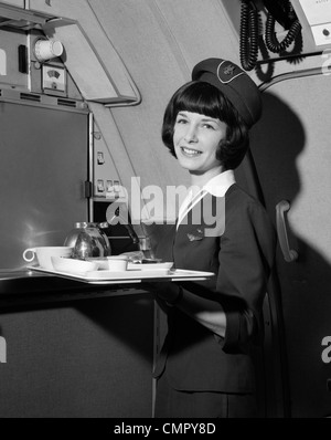 1960 SMILING FLIGHT ATTENDANT HOLDING TRAY WITH COFFEE SERVICES Banque D'Images