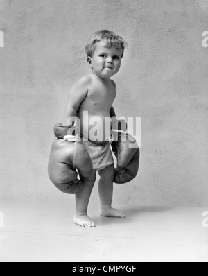 1930 Bébé garçon enfant en portant des gants de boxe surdimensionnée Banque D'Images