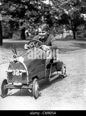 1930 BOY DRIVING HOME CONSTRUIT MAINTENANT LE VOLANT DE VOITURE DE COURSE Banque D'Images