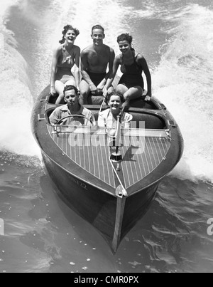 Années 1930, DES COUPLES CINQ HOMMES ET FEMMES ÉQUITATION DANS RUNABOUT BATEAUX Banque D'Images