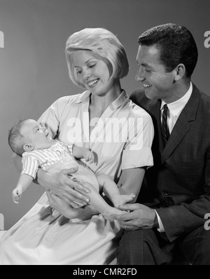 1960 Heureux PÈRE ET MÈRE souriant à leur bébé Banque D'Images