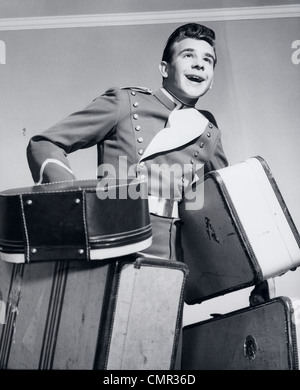 1950 GROOM SMILING transportant quatre sacs d'assurance Banque D'Images