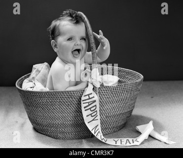 1940 BABY SITTING DANS PANIER EN OSIER AVEC BONNE ANNÉE BANNER STUDIO PISCINE Banque D'Images