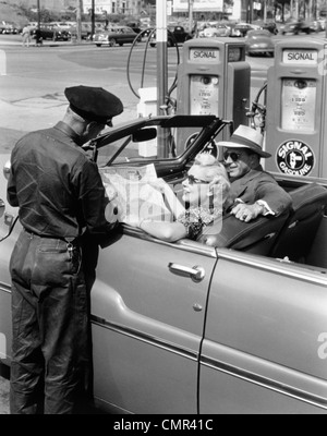 1950 COUPLE WITH MAP EN VOITURE DÉCAPOTABLE ANCIENNES DIRECTIONS DE PRÉPOSÉ DE STATION Banque D'Images