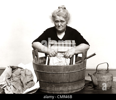 Années 1920 Années 1930 Années 1940 SENIOR WOMAN LAVER LES VÊTEMENTS À L'ANCIENNE BAIGNOIRE EN BOIS ET BORDAGE Banque D'Images