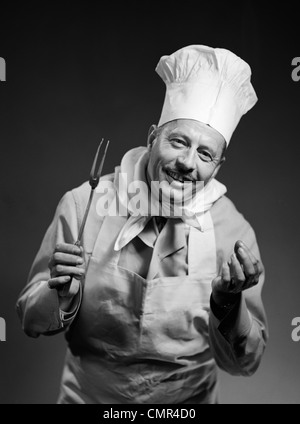 1950 MAN SMILING CHEF AVEC DES MAINS À L'INTÉRIEUR DE L'APPAREIL PHOTO À Banque D'Images