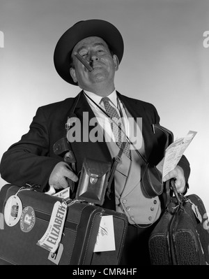 Années 1950 Années 1960 TÊTE PORTRAIT DE CIGARE'TRANSPORTANT BEAUCOUP DE BAGAGES LOOKING AT CAMERA Banque D'Images