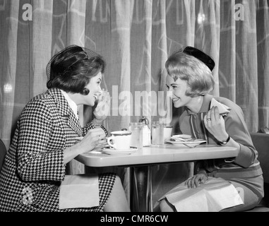 1960 DEUX FEMMES COMMÉRER AU DÉJEUNER AU RESTAURANT Banque D'Images