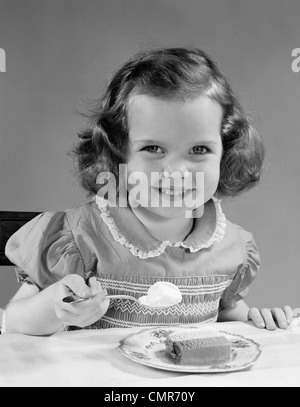 1950 LITTLE GIRL EATING ICE CREAM SMILING Banque D'Images