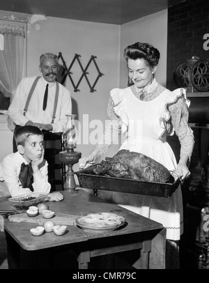 1950 FAUX DU 20ème siècle dîner de Thanksgiving SMILING MOTHER MONTRANT Rôti de dindon à l'HEUREUX MARI ET SURPRIS Banque D'Images