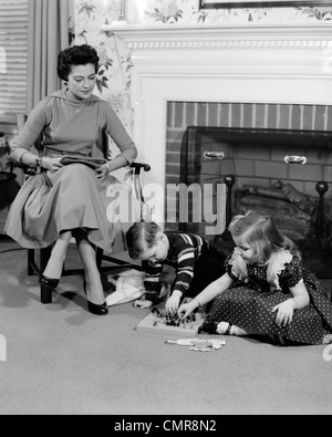 1950 REGARDER Mère Fils Fille joue une partie EN FACE DE CHEMINÉE Banque D'Images