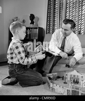 1950 PÈRE ET FILS JOUER AVEC JEU JOUET COWBOY DANS LA SALLE DE SÉJOUR PISCINE Banque D'Images