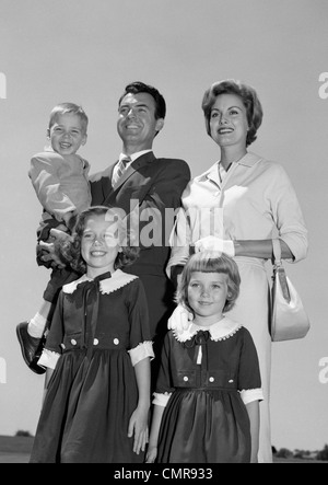 1960 PORTRAIT SMILING FAMILY PÈRE MÈRE DEUX FILLES FILS STANDING TOGETHER OUTDOORS Banque D'Images